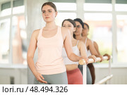 Young girl practicing first arm position holding by ballet barre. Стоковое фото, фотограф Яков Филимонов / Фотобанк Лори