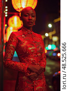 Bald woman wearing a red dress stands on a city street, her figure distinctly contrasting with the urban surroundings. Стоковое AI-изображение, AI-художник Данила Большаков / Фотобанк Лори