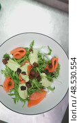 Skilled culinary professional garnishing gourmet salmon salad with golden croutons, creamy avocado spread, fresh arugula on sleek kitchen counter. Стоковое видео, видеограф Данил Руденко / Фотобанк Лори