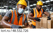 Two men wearing orange vests and hard hats are working in a warehouse. Стоковое AI-изображение, AI-художник Ярославский Максим / Фотобанк Лори