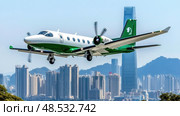 A small green and white airplane is flying over a city. Стоковое AI-изображение, AI-художник Ярославский Максим / Фотобанк Лори