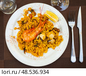 Paella made of rice and different seafood served in plate with table appointments. Стоковое фото, фотограф Яков Филимонов / Фотобанк Лори