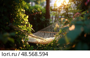 Hammock nestled among lush greenery with sunlight filtering through at sunset. Стоковое AI-изображение, AI-художник Сергей Толмачёв / Фотобанк Лори