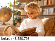 Веселый мальчик читает книгу, сидя в уютном кресле. Теплый летний день. Стоковое AI-изображение, AI-художник Щеголева Ольга / Фотобанк Лори