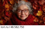 An elderly woman with curly gray hair and glasses smiles contentedly as she rests in vibrant autumn leaves, embodying warmth and tranquility. Стоковое AI-изображение, AI-художник Данила Большаков / Фотобанк Лори
