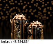 Elegant black and gold gift boxes with shiny golden bows and festive bokeh background. Perfect for luxury holiday or celebration themes. 3D render. Стоковое AI-изображение, AI-художник Татьяна Грачева / Фотобанк Лори