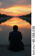 Mourner Whispering Prayers by a Twilight River, Reflections at Sunset Evoke Deep Emotion and Spirituality. Стоковое AI-изображение, AI-художник Sergey Grishin / Фотобанк Лори