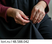 Close-up of a Woman's Hands Sewing a Black Banner for Ashura, Fingers Trembling With Focus and Determination. Стоковое AI-изображение, AI-художник Sergey Grishin / Фотобанк Лори