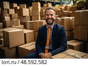 Ыmiling man in a suit and orange tie sits on pile of cardboard boxes. Стоковое AI-изображение, AI-художник Данила Большаков / Фотобанк Лори
