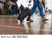 Busy Train Station Scene with Traveler Pulling Rolling Suitcase Through Concourse. Стоковое фото, фотограф Zydrius Tartenis / Фотобанк Лори