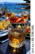 A table with a glass of liquor and a plate of food. Стоковое AI-изображение, AI-художник Ярославский Максим / Фотобанк Лори