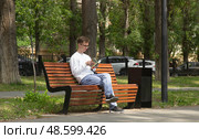 Молодой человек читает книгу в сквере на лавочке. Саратов. Редакционное фото, фотограф Евгений Будюкин / Фотобанк Лори