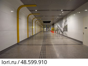 Singapore, Singapore - 4 April 2025: Interior view of underground MRT station passageway connecting to Exit 1 and 2 for Gardens by the Bay, showing modern subway architecture with directional signs and commuters. Редакционное фото, фотограф Татьяна Терехина / Фотобанк Лори