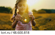 Golden Hour Discovery: Young Girl with Long Hair Holding a Mysterious Handcrafted Object in a Sunlit Field. Evocative scene for storytelling or childhood themes. Стоковое AI-видео, аниматор Данила Большаков / Фотобанк Лори