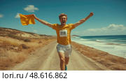 A joyful runner with bib number 219 waves a yellow flag while sprinting down a coastal path under bright blue skies. Стоковое AI-изображение, AI-художник Данила Большаков / Фотобанк Лори