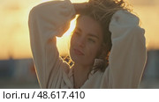 Young woman wearing earbuds enjoying golden hour sunset. Стоковое видео, видеограф Константин Шишкин / Фотобанк Лори
