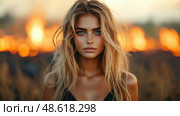 A woman with flowing hair stands strongly in front of flames, capturing the intensity of the moment as the sun sets behind her. Стоковое AI-изображение, AI-художник Данила Большаков / Фотобанк Лори