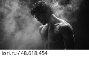 A muscular individual stands quietly, enveloped in steam, showcasing a moment of reflection and physical strength in a dimly lit environment. Стоковое AI-изображение, AI-художник Данила Большаков / Фотобанк Лори