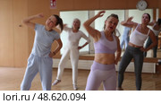 Positive women practicing group dancing in modern fitness center. Стоковое видео, видеограф Яков Филимонов / Фотобанк Лори