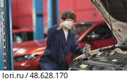 Qualified mechanic in a car service checks the amount of oil in the car with a dipstick. Car service employee inspects the car and changes the engine oil. Стоковое видео, видеограф Яков Филимонов / Фотобанк Лори