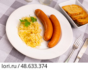 Sausages served with sauerkraut, bread and parsley. Стоковое фото, фотограф Яков Филимонов / Фотобанк Лори
