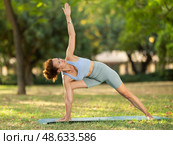 Woman practicing yoga in garden, performing Anjaneyasana, or Crescent Moon Pose. Стоковое фото, фотограф Яков Филимонов / Фотобанк Лори