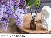 The aroma diffuser. Lilac-scented spring perfumes for the home in a glass bottle with chopsticks as an air freshener in the house. Aromatherapy, cozy atmosphere, comfort and relaxation. Стоковое фото, фотограф Photojuli / Фотобанк Лори