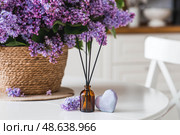 The aroma diffuser. Spring aromatic lilac perfumes for the home in a glass bottle with sticks as an air freshener in the house and soap. Aromatherapy, cozy atmosphere, comfort and relaxation. Стоковое фото, фотограф Photojuli / Фотобанк Лори
