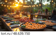 A lively outdoor gathering features an array of shared dishes and wine, illuminated by warm twinkling lights as the sun sets in the background. Стоковое AI-изображение, AI-художник Данила Большаков / Фотобанк Лори