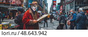 A street performer, wearing clown makeup and a vibrant costume, engages passersby while holding a sign in the lively atmosphere of Times Square. Стоковое AI-изображение, AI-художник Данила Большаков / Фотобанк Лори