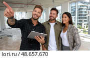 A man and two women are standing in a room, with the man pointing to a tablet. Стоковое AI-изображение, AI-художник Ярославский Максим / Фотобанк Лори