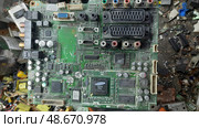 Old circuit board lying among electronic waste in a recycling center, showcasing complex components and connections. Стоковое фото, фотограф Александра Рублева / Фотобанк Лори