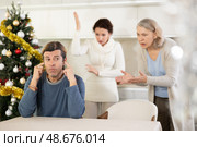 Elderly mother and woman during family quarrel accuse adult man on Christmas Eve. Стоковое фото, фотограф Яков Филимонов / Фотобанк Лори