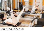 Guy doing legs exercises with straps on Pilates reformer. Стоковое фото, фотограф Яков Филимонов / Фотобанк Лори