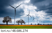 Dark shelf cloud preceding a severe thunderstorm at a wind turbine park. Beautiful thunderstorm black clouds and clouds hanging over the ground. Стоковое AI-изображение, AI-художник ALLA YURTAYEVA / Фотобанк Лори