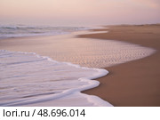 Serene sunset beach with gentle waves on sandy shore. Стоковое AI-изображение, AI-художник Башкирова Анна / Фотобанк Лори