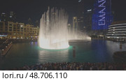 UAE, Dubai, 12 December 2024: The famous musical dancing fountain show in Dubai next to the Dubai Mall at dusk, people taking photos and videos with their smartphones, the old bazaar and skyscrapers. Редакционное видео, видеограф Vladimir Drozdin / Фотобанк Лори
