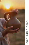 A child's small hands holding a clay water jug, symbolizing the thirst of Imam Hussain family, under the fading light of sunset. Стоковое AI-видео, аниматор Sergey Grishin / Фотобанк Лори