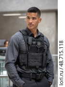 Security guard wearing tactical vest and radio looking away. Стоковое AI-изображение, AI-художник Юрий Поздников / Фотобанк Лори