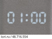 Digital timer showing 01:00 minutes displayed through mesh textile surface. Macro shot of illuminated electronic countdown digits. Technology and timekeeping concept for design and print. Стоковое фото, фотограф Андрей Журавлев / Фотобанк Лори