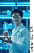 A researcher proudly displays a luminous capsule, highlighting groundbreaking findings in a cutting-edge laboratory environment. Стоковое AI-изображение, AI-художник Данила Большаков / Фотобанк Лори