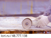 Close-up of the hands of a worker sawing an asbestos slab on a grinding machine. Dust during grinding of the coating... Стоковое фото, фотограф lyudmila Soloveva / Фотобанк Лори