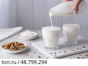 Pouring homemade kefir, buttermilk or yogurt with probiotics. Yogurt flowing from glass bottle on light background. Probiotic cold fermented dairy drink. Trendy food and drink. Copy space. Стоковое фото, фотограф Наталия Попова / Фотобанк Лори