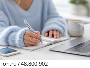 Focused Young Woman Taking Notes, Morning Study Session with Coffee in Kitchen. Сосредоточенная девушка делает заметки, утреннее занятие с кофе на кухне. Стоковое AI-изображение, AI-художник Katsiaryna Repich / Фотобанк Лори