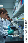 A pharmaceutical lab, scientists in lab coats analyzing samples under microscopes, with shelves of glass vials and sterile white laboratory outfits. Стоковое AI-видео, аниматор Sergey Grishin / Фотобанк Лори