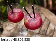 Delicious red cocktail with ice in a stemmed glass on a wooden surface. Стоковое фото, фотограф Татьяна Яцевич / Фотобанк Лори