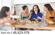 Upset young brunette sitting at home table during cozy friendly gathering while attentive besties comforting and supporting her, discussing problems and giving advice over glass of wine. Стоковое видео, видеограф Яков Филимонов / Фотобанк Лори