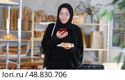 European Muslim girl customer holds pastry on disposable plate and recognizes it using app. Стоковое видео, видеограф Яков Филимонов / Фотобанк Лори
