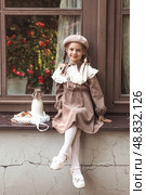 Vintage accessories and retro-style clothes. A small, beautiful girl with bows in her hair, in a beige dress and a beret outdoors with bagels and milk in a string bag. Стоковое фото, фотограф Photojuli / Фотобанк Лори