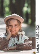 Vintage women's accessories and retro-style clothing. A small, beautiful girl with bows in her hair, in a beige dress and a beret outdoors. Стоковое фото, фотограф Photojuli / Фотобанк Лори